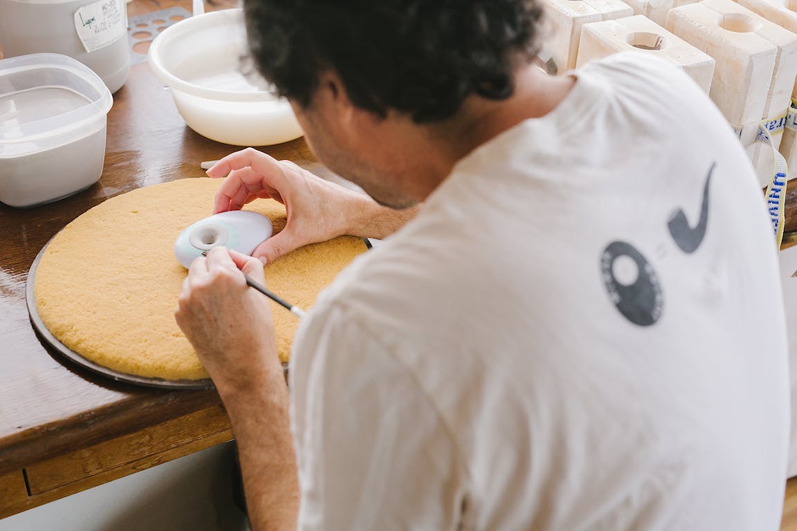 A person works on intricate details of a ceramic pipe.
